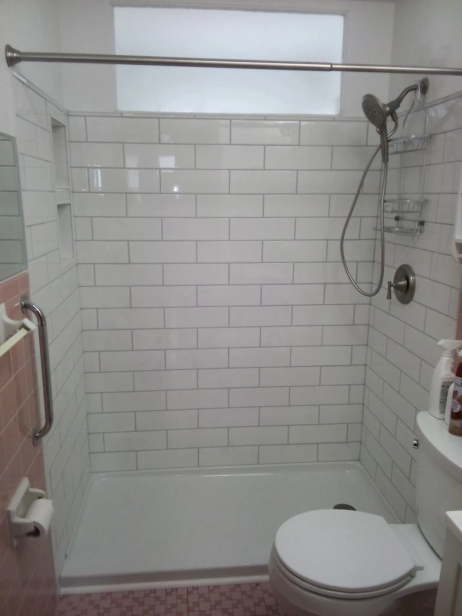 The finished alcove in white subway tile with two recessed niches and a new shower valve