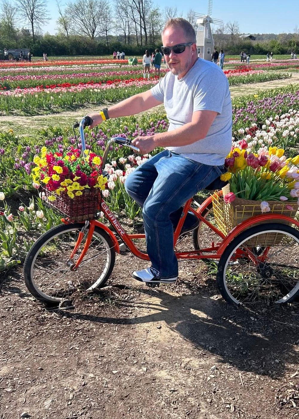 Matt riding an orange trike through a tulip field