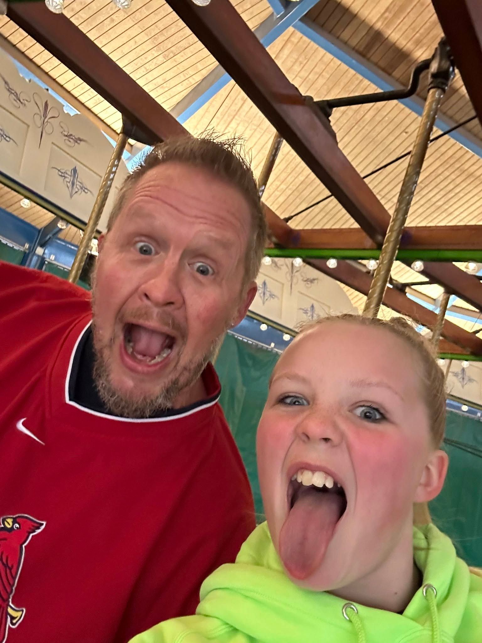 Matt and his daughter making faces on a carousel