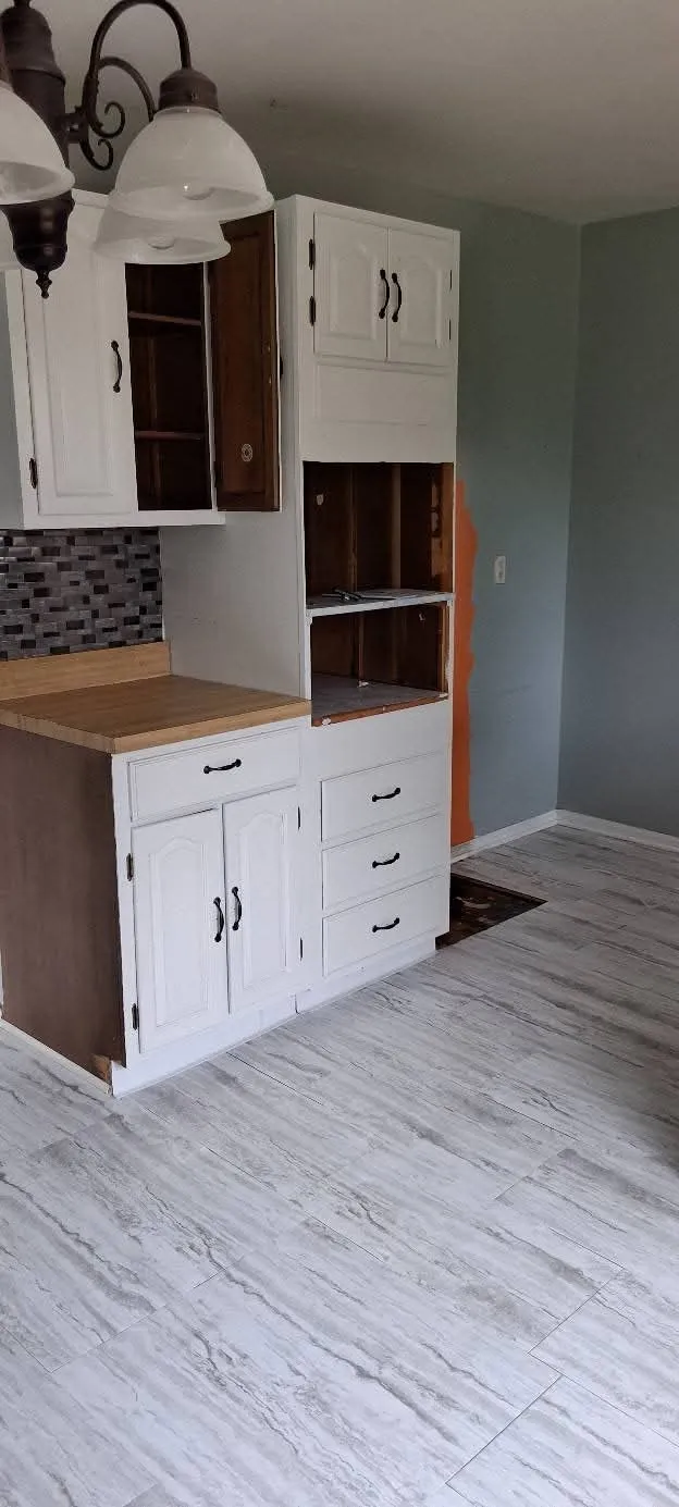 A cabinet run mid-job, with new tile-plank flooring already down and the upper cabinets being reworked