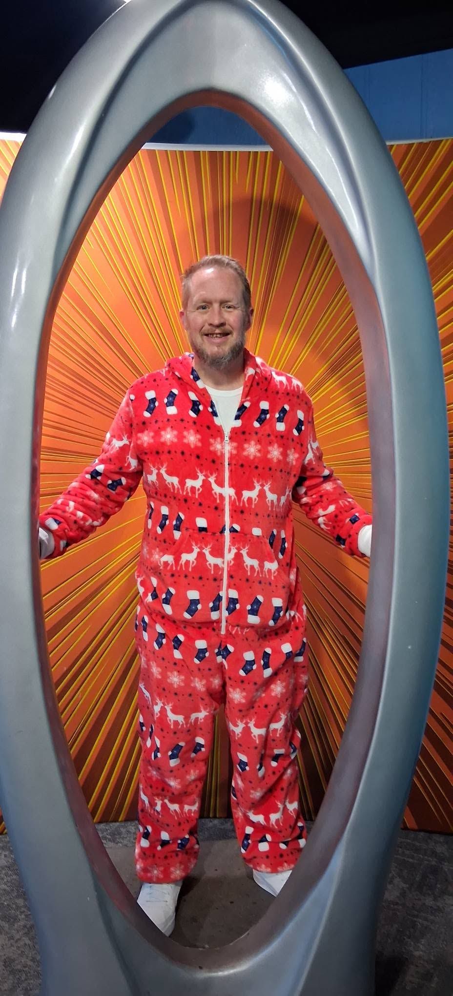 Matt in a Christmas onesie standing in a silver portal frame