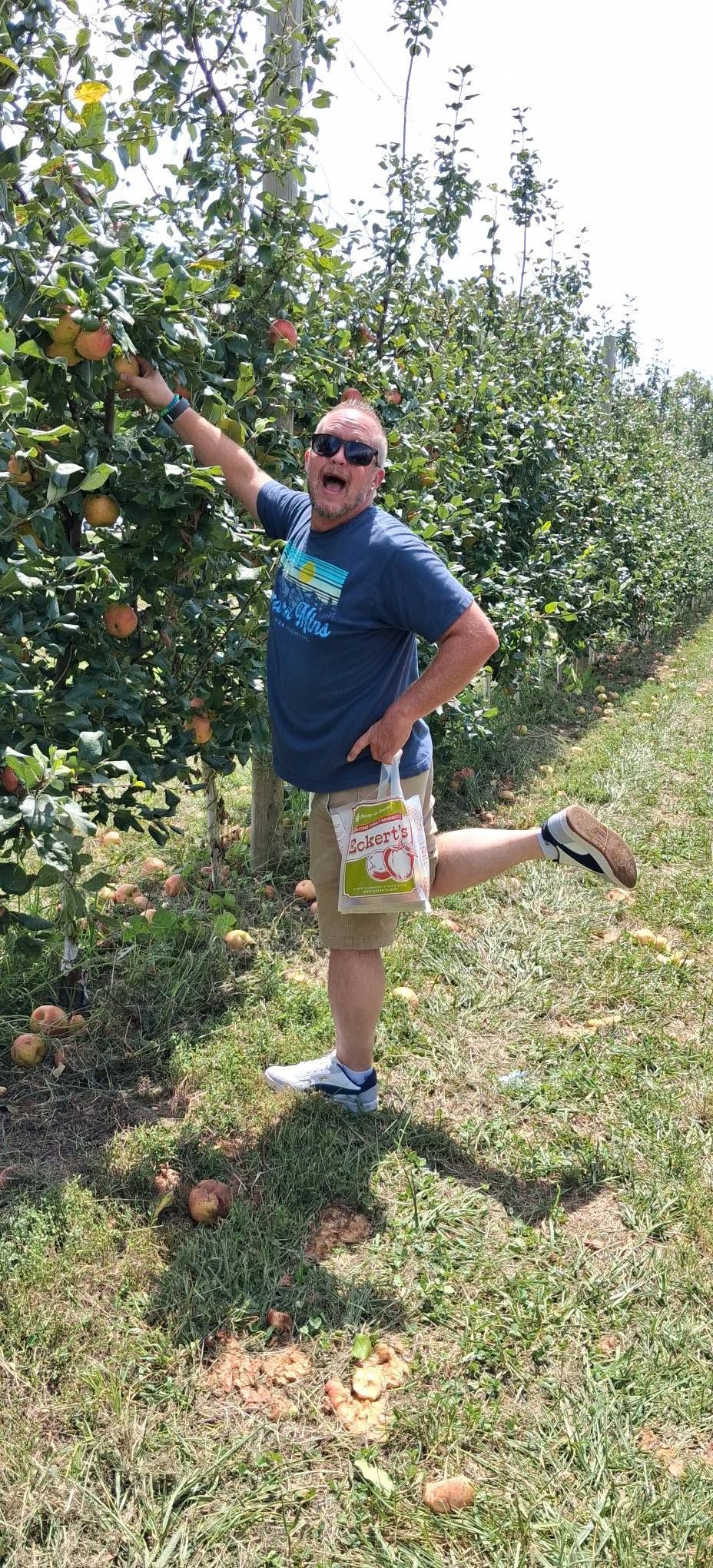 Matt kicking up a leg while picking apples in an orchard