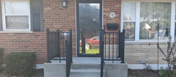 The same stoop with a black iron railing installed along the steps and across the landing